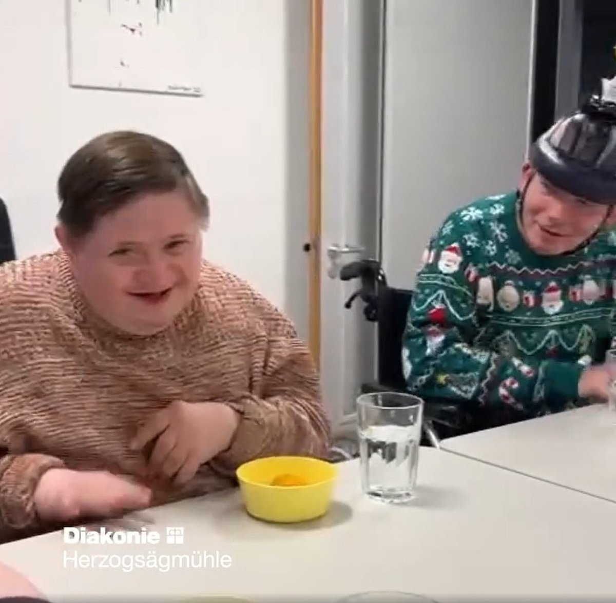 Zwei Personen mit Behinderung am Tisch.