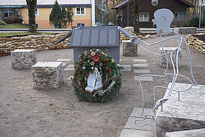 Ort der Erinnerung in Herzogsägmühle mit Gedenktafeln und großem Kranz.