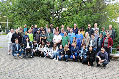 Eine große Gruppe von Auszubildenden und Ausbildern stehen zusammen und schauen in die Kamera