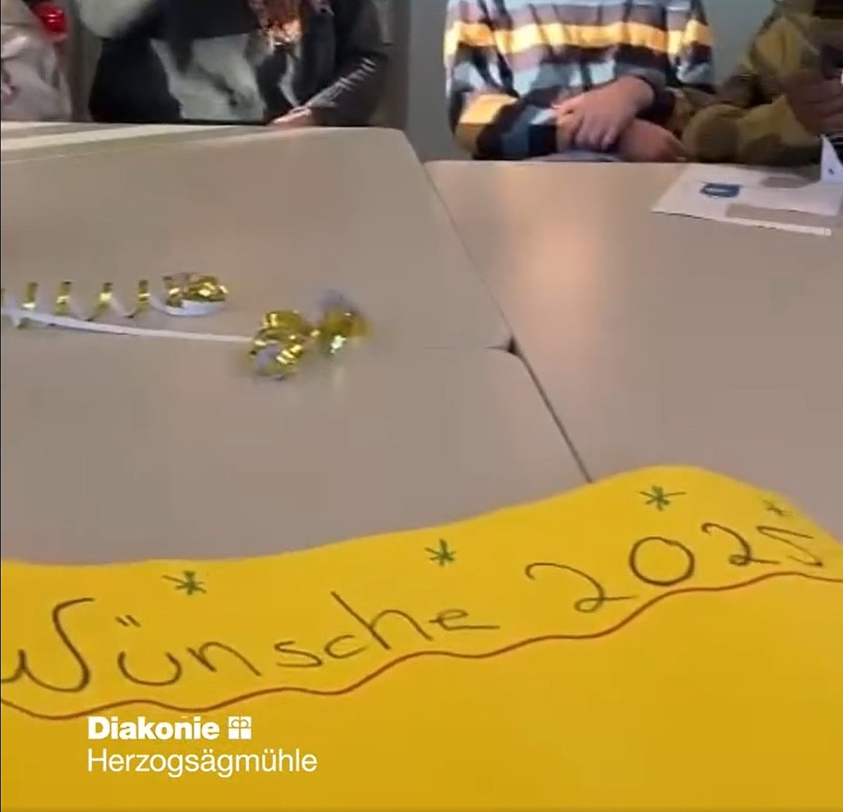 Auf einer gelben Pappe auf einem Tisch steht Wünsche 2025.