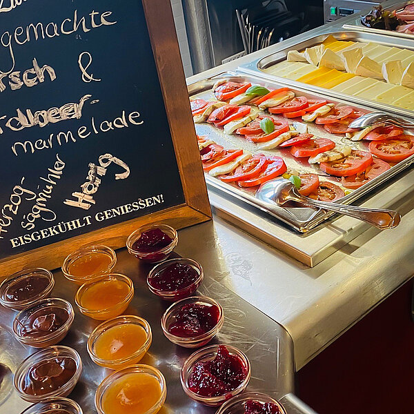 Teil vom Frühstücksbuffet mit Marmelade in Schälchen sowie Tomate-Mozarella und Käse auf einer Platte.